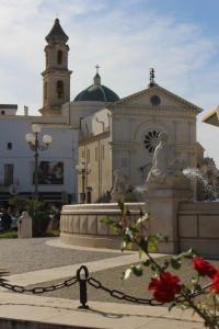 Platz mit einem Springbrunnen und dem Blick auf zwei Kirchen in der Altstadt von Mola di Bari in Apulien.
