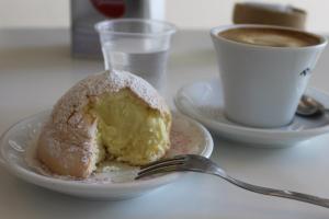 Ein typisch süditalienisches Frühstück: Venusbrust, auf Italienisch "tette di venere", und ein Capuccino und ein Glas Wasser stehe auf einem Tisch in einer Bar.