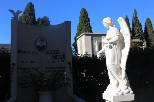 Ein blütenweißer Engel und eine Steintafel kennzeichnen die letzte Ruhestätte von Rocco Dicillo auf dem Friedhof in Triggiano, Apulien.