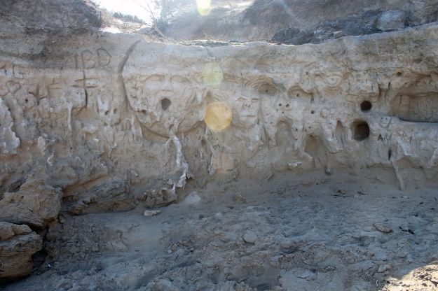 In einen Sandsteinfelsen eines Strandabschnitts des Naturschutzgebietes von Torre Guaceto in Apulien haben künstlerisch begabte Besucher Gesichter geschnittst.