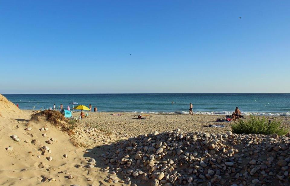 Gelber Sand am Strand der Malediven des Salento bei Santa Maria di Leuca, auf dem sich noch einige Touristen sonnen oder spazieren gehen. Dahinter erstreckt sich das weite Meer.