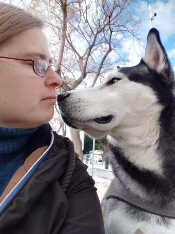 Ein Husky und Corinna, die Auswanderin nach Apulien schauen sich tief in die Augen und haltne ein Zwiegespräch vor dem wolkigen Frühlingshimmel im März.