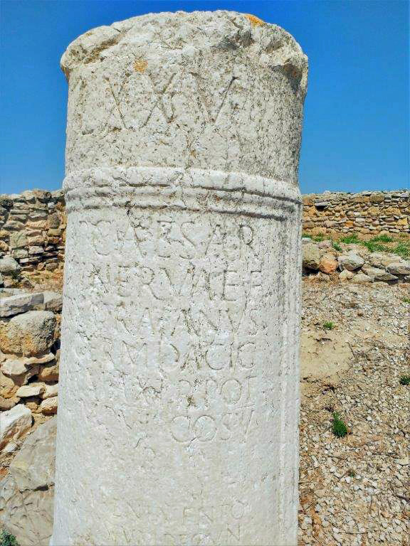 Eine antike Säule mit Inschriften steht zwischen den Ruinen der mittelalterlichen Stadt Canae in Canne della Battaglia, Apulien.