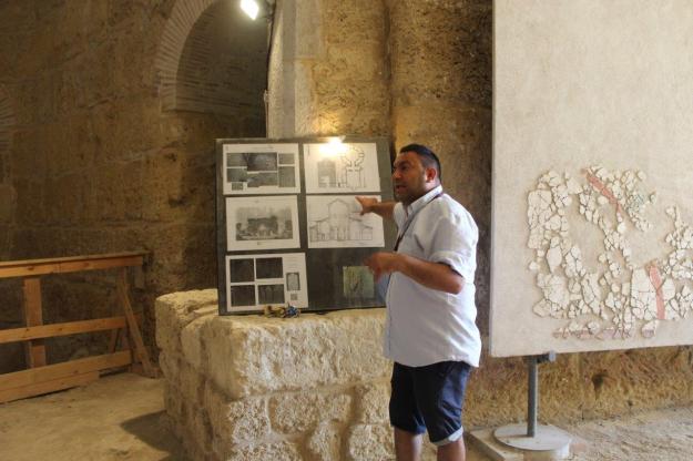 Der engagierte Führer Andrea erklärt mit Hilfe von Abbildungen das ursprüngliche Aussehen und die Bauphasen der Ruine der Täuferkirche des Heiligen Johannes in der Ausgrabungsstätte Parco Archeologico di San Giovanni in Canosa, Apulien.