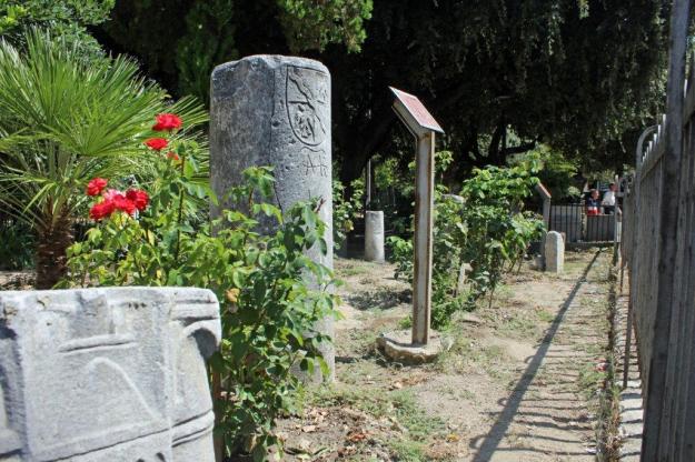 Fundstücke aus den Ausgrabungsstätten von Canosa stehen wzsichen Rosen und Palmen im Park der Villa Comunale in Canosa, Apulien.