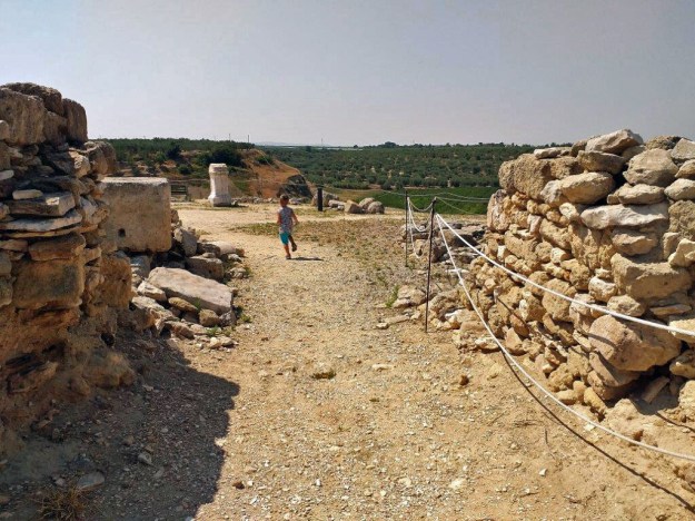Ein Kind läuft auf einem Sandweg zwischen den Mauern der Ruinen der mittelalterlichen Stadt Cannae, heute Canne della Battaglia in Apulien.