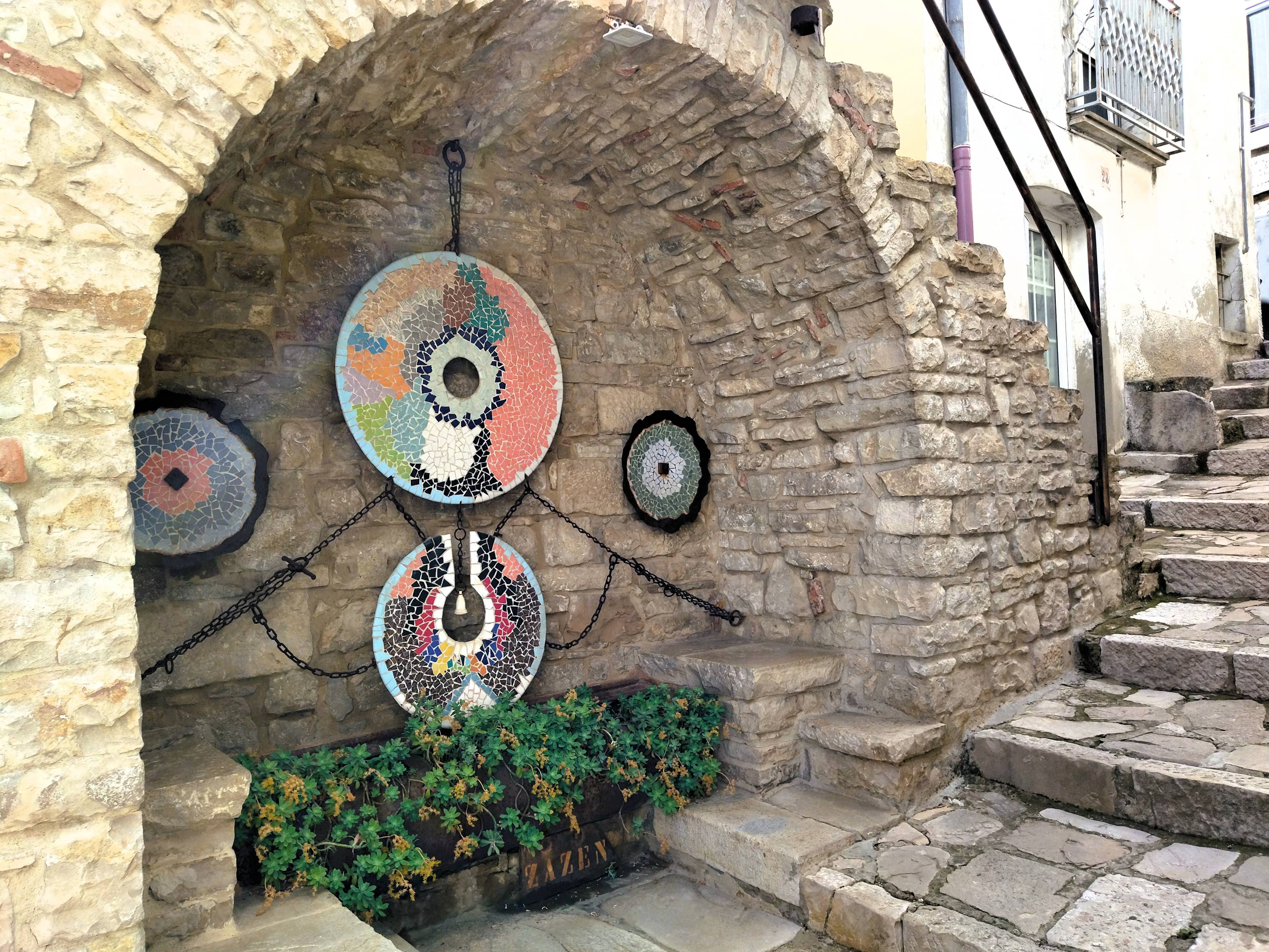 Bogen mit Sitzgelegenheit in einer Hauswand mit Mosaiken aus Scherben von altem Geschirr, Forenza, Basilikata, Süditalien, Street Art