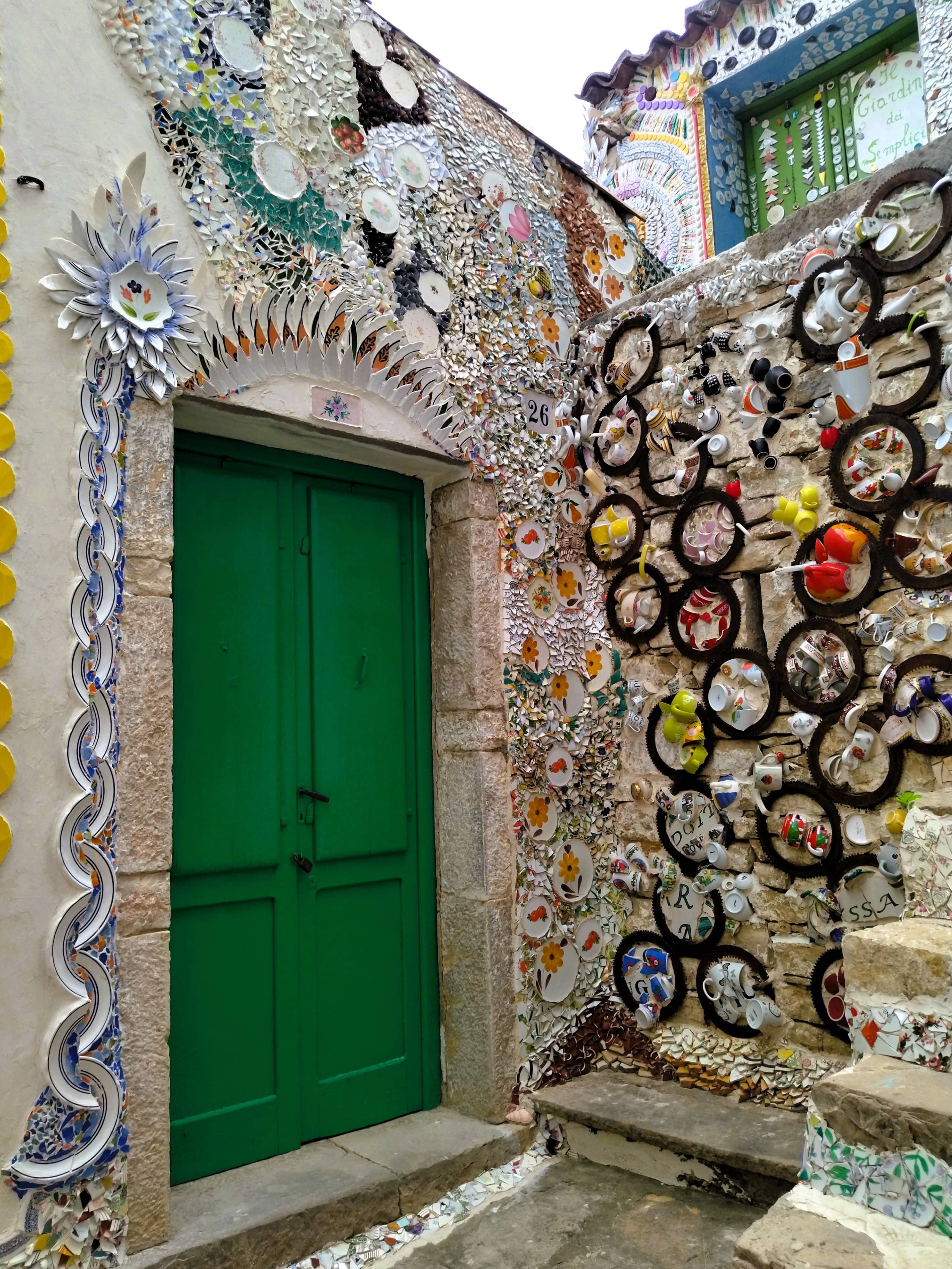 Hauswand und grüne Tür mit Mosaiken aus Scherben von altem Geschirr, Forenza, Basilikata, Süditalien, Street Art