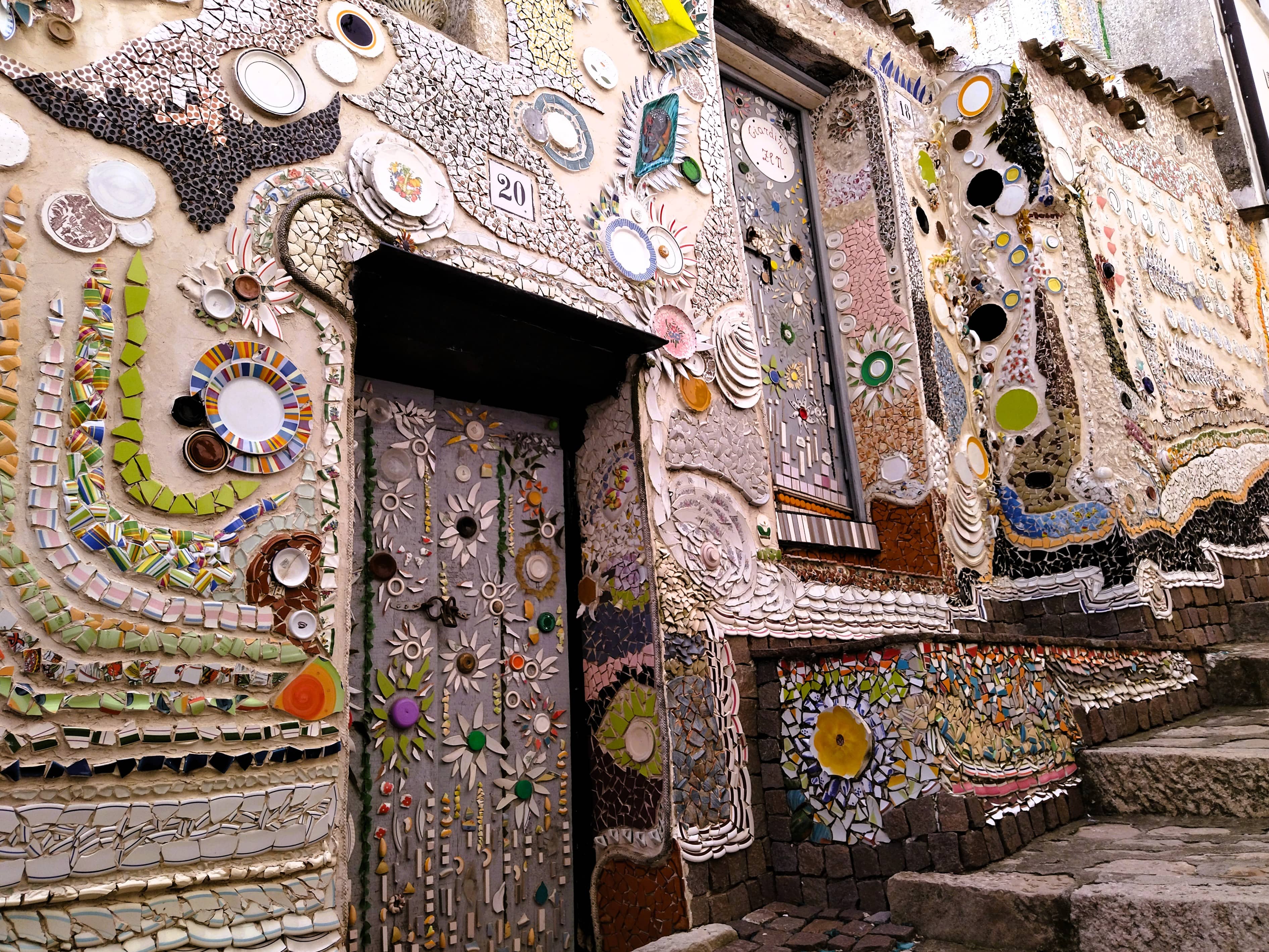 Hauswand, tür und Straße dekoriert mit Mosaiken aus Scherben von altem Geschirr, Forenza, Basilikata, Süditalien, Street Art