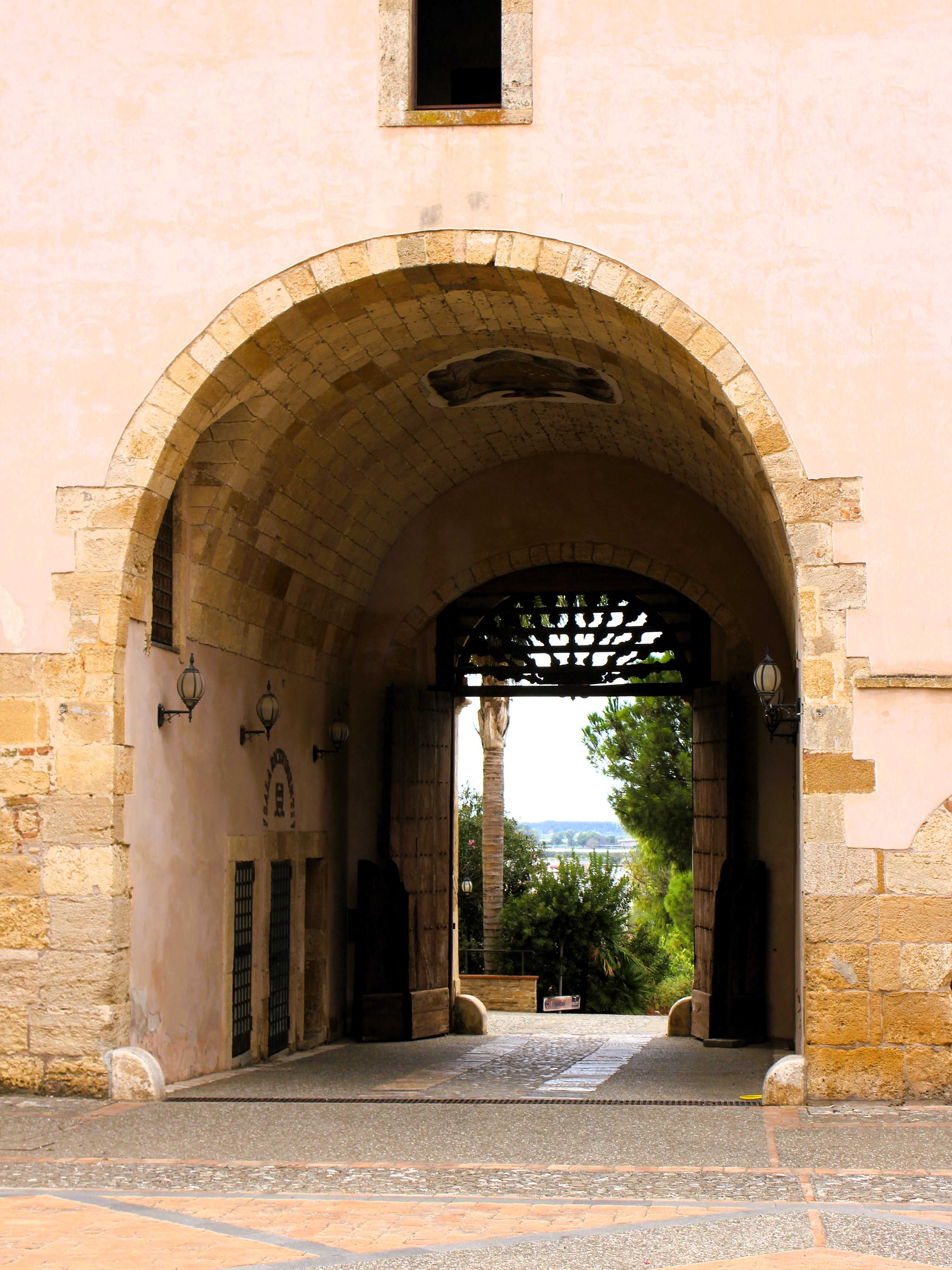 Der Blick aus dem Eingangstor des Castello di Policoro in Basilikata fällt auf Büsche und Palmen, welche die Stadt zugunsten eines weiten Blickes auf die Metapontoebene verdeckt.