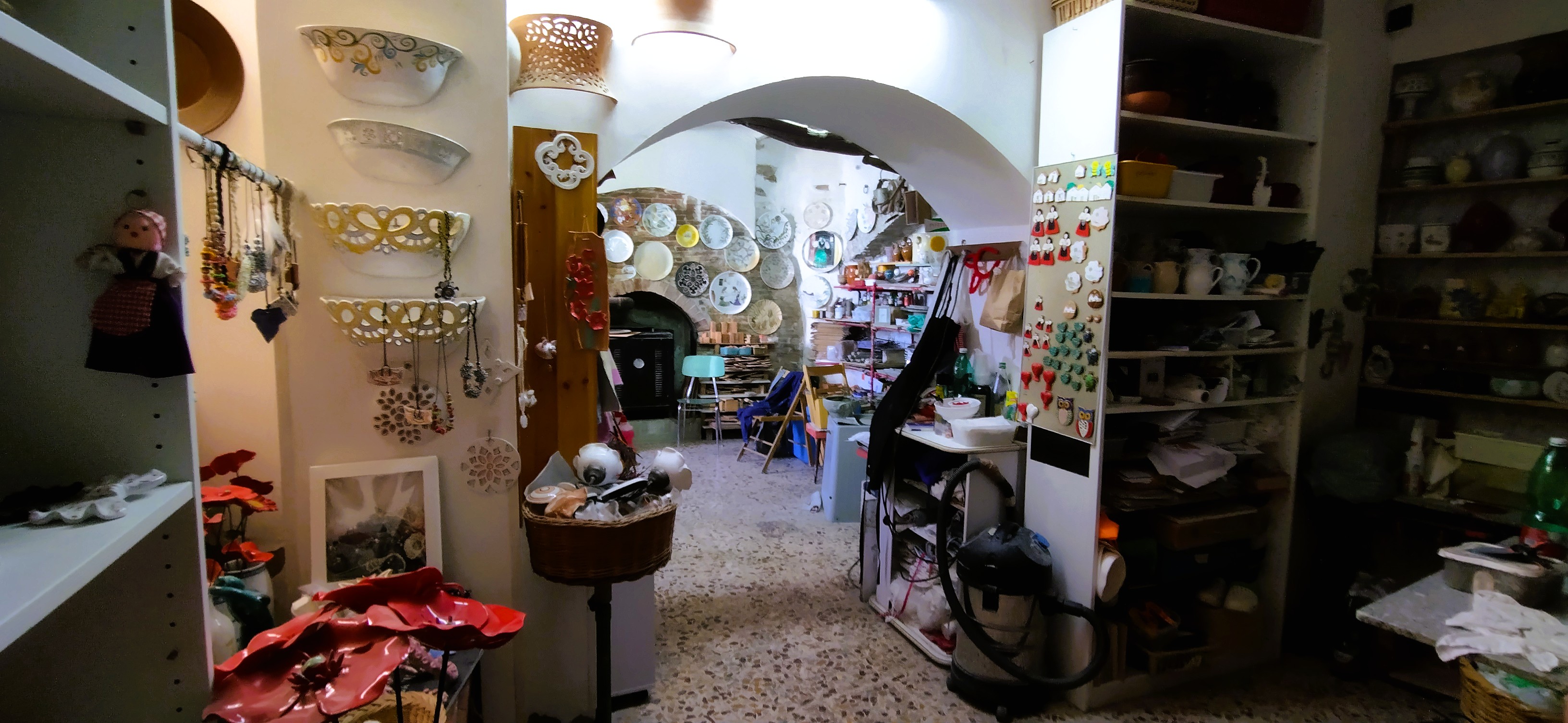 Hohe Regale, Übertöpfe und Teller aus Keramik an den Wänden und ein Durchgang in der Keramikwerkstatt der Künstlerin Annamaria Pagliei in Pisticci Basilikata.