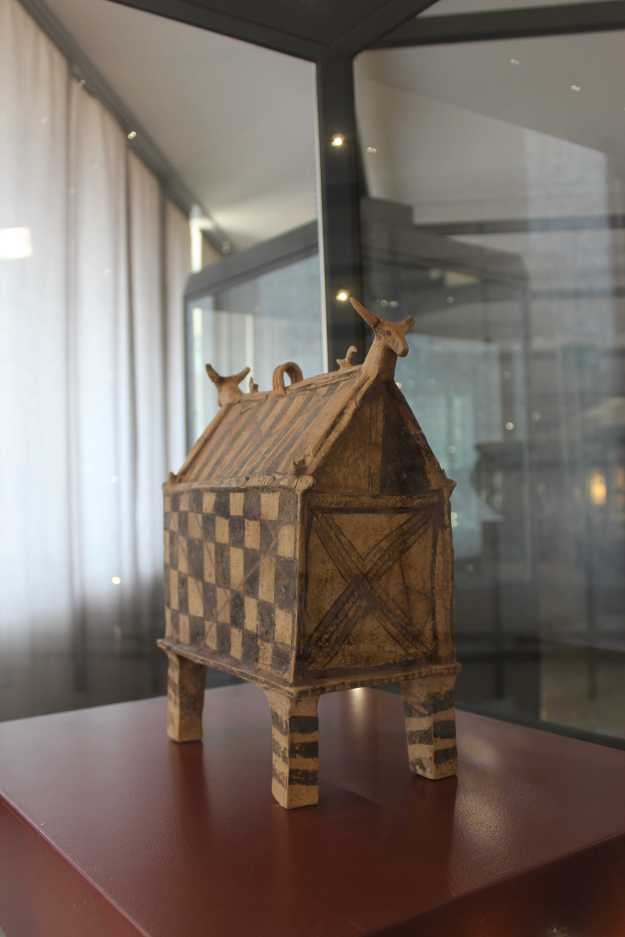 Eine originelle Aufbewahrungsbox aus der hellenistischen Zeit im Archäologischen Nationalmuseum Siritide in Policoro, Basilikata, hat die Form eines Hauses mit Spitzdach auf vier Stelzen und ist am "Giebel" geschmückt mit Tierköpfen.
