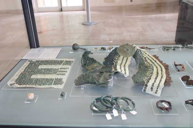 Eine Vitrine mit Grabbeigaben aus der Eisenzeit zeigen Metallringer und dekorierte Stoffe im Archäologischen Nationalmuseum Siritide in Policoro, Basilikata