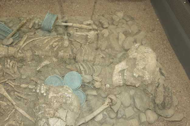 Darstellung eines Grabs aus der Eisenzeit mit einem Skelett und Grabbeigaben in einer Vitrine des Archäologischen Nationalmuseums Siritide in Policoro, Basilikata