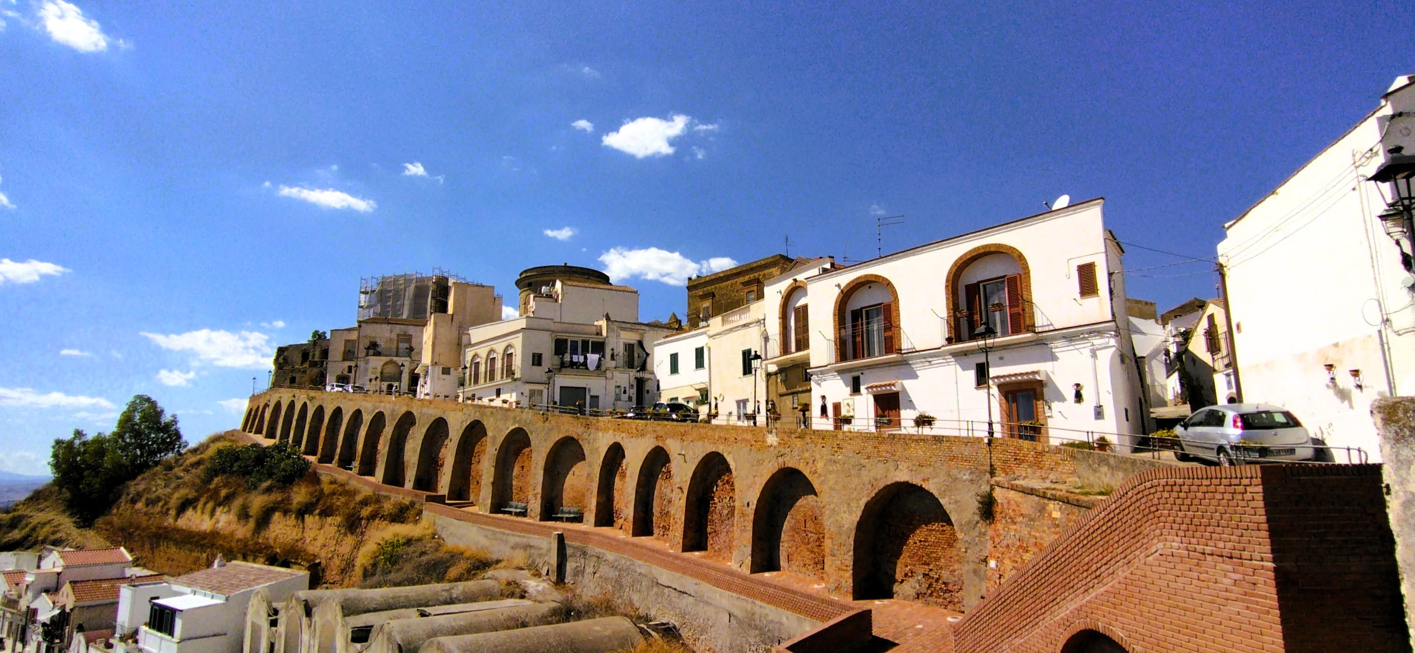 In Pisticci in der Basilikata führt eine Straße von der Kirche Sankt Peter und Paul zur Ruine des Kastells. Eine Mauer aus Backsteinen schützt den Hang vor dem Abrutschen.