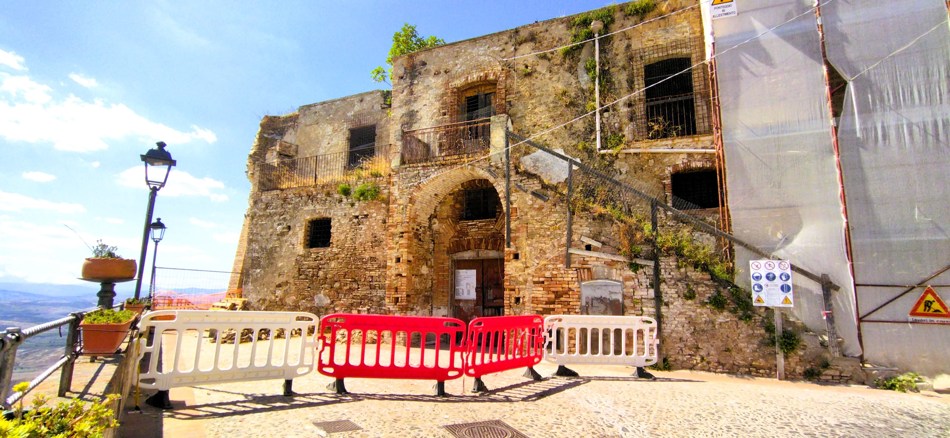 Das Kastell von Pisticci ist eine Ruine. Eine Absperrung, Schilder und verhüllte Wände zeugen von Restaurierungsarbeiten.