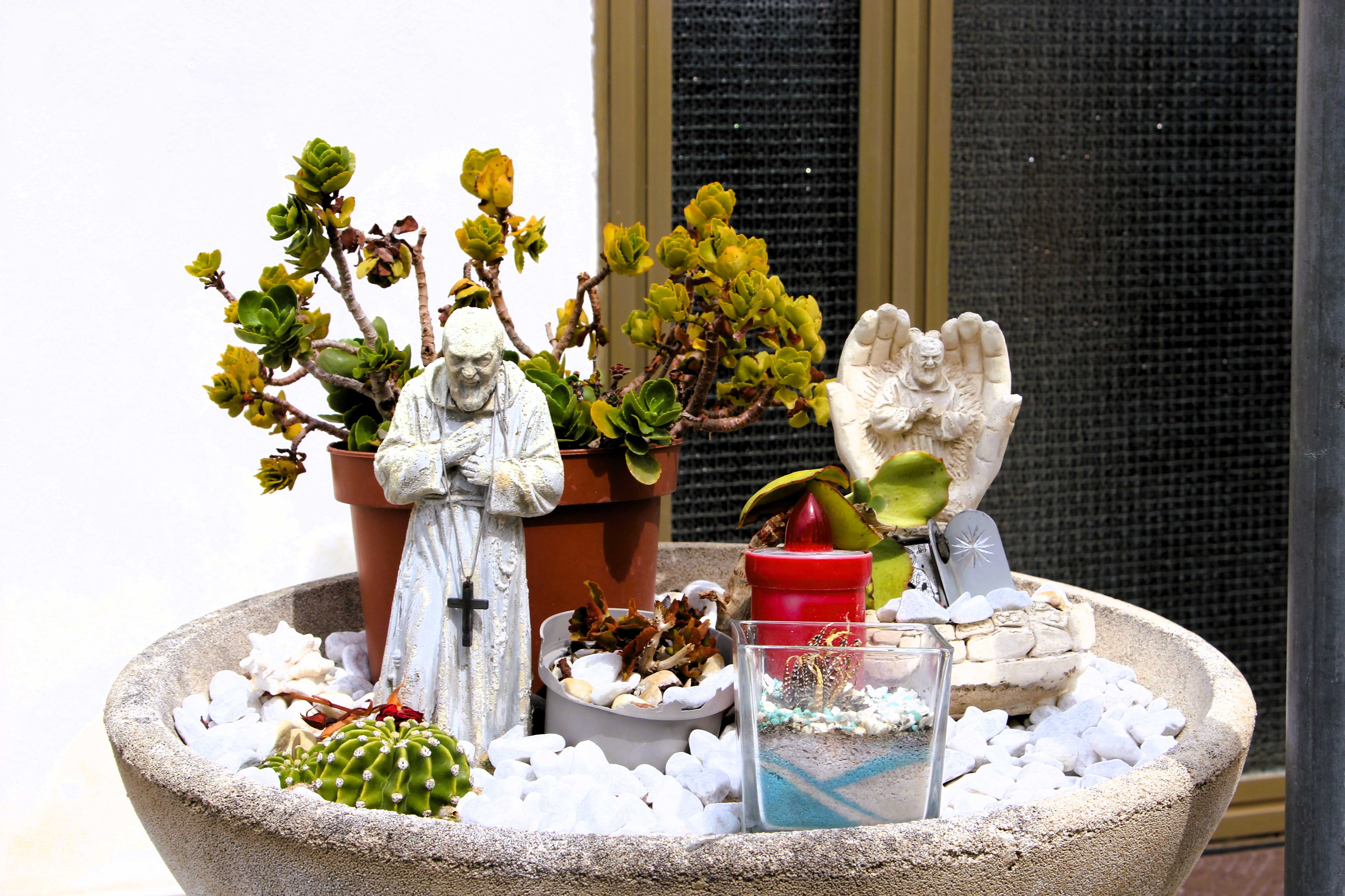 Vor der Tür eines Hauses in Policoro stehe ein kleiner Garten in einer Blumenschale und zeigt die Verbundenheit mit Padre Pio durch zwei kleine Statuten.