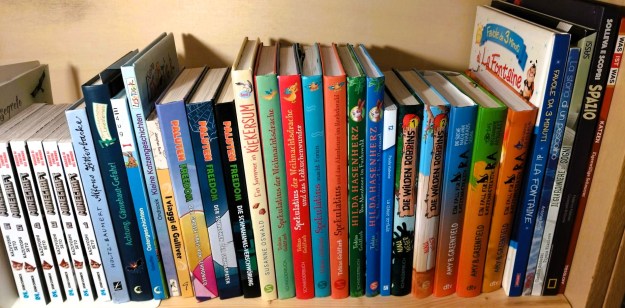 In einem Bücherragel in einem zweisprachigen Zuhause stehen deutsche und italienische Kinderbücher