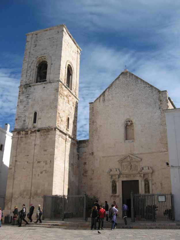 Die weiße Kirche "Chiesa Matrice di Santa Maria Assunta" in Polignano a Mare erhebt sich in den blauen Himmel mit weißen Schleierwolken.