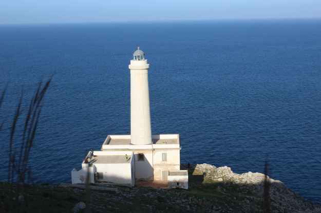 Der kalkweiße Leuchtturm von Punta Palascia vor einem tiefblauen, leicht bewegtem Meer