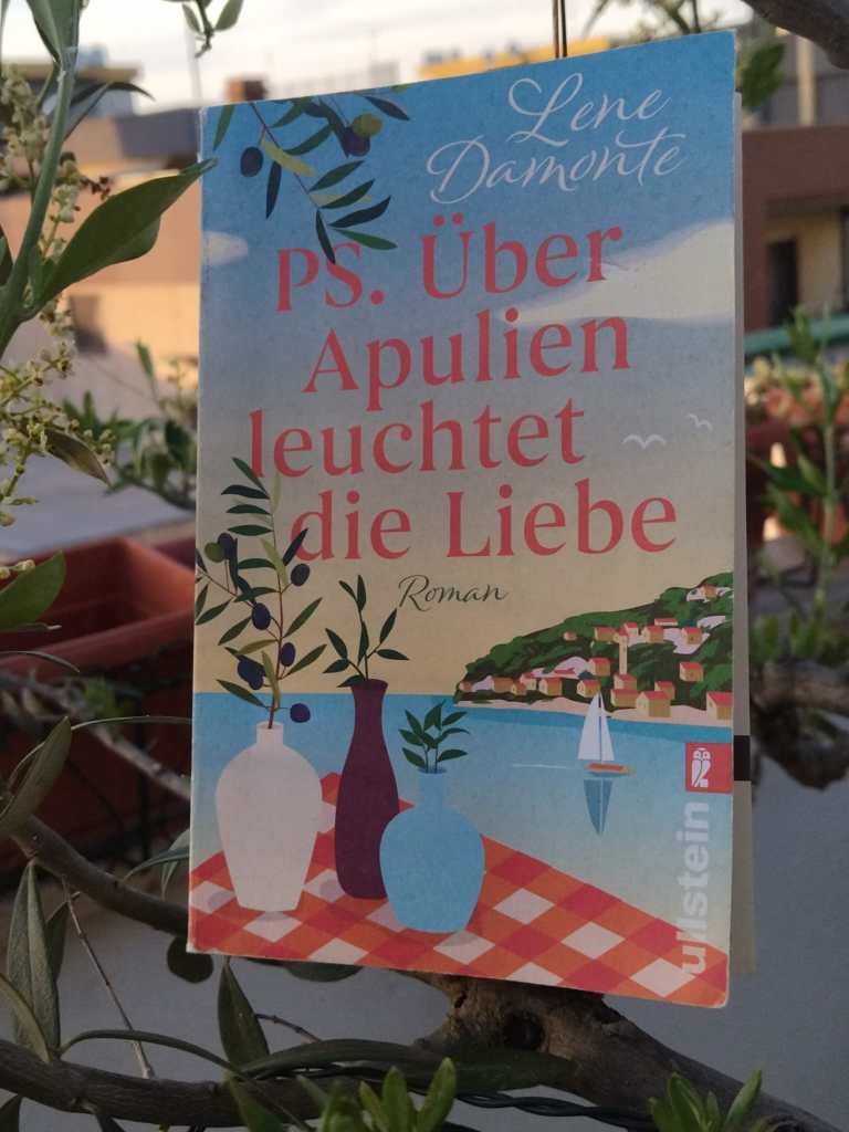 Das Foto zeigt den Roman "PS. Über Apulien leuchtet die Liebe" von Lene Damonte in einem Olivembaum.